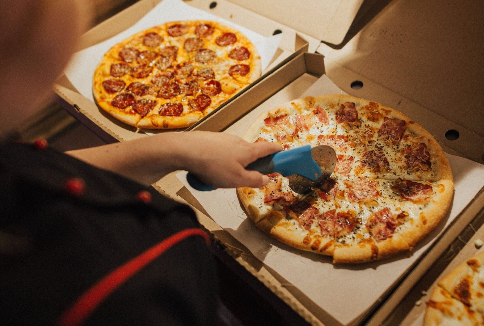persona cortando una pizza con un cortador de pizza