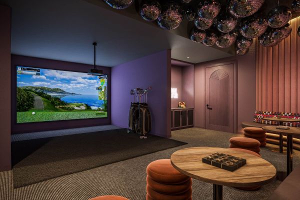 Immersive entertainment lounge at VERVE Orlando featuring a large projector screen, cozy seating, moody purple walls, and playful ceiling decor—perfect for gaming, movie nights, or streaming marathons.