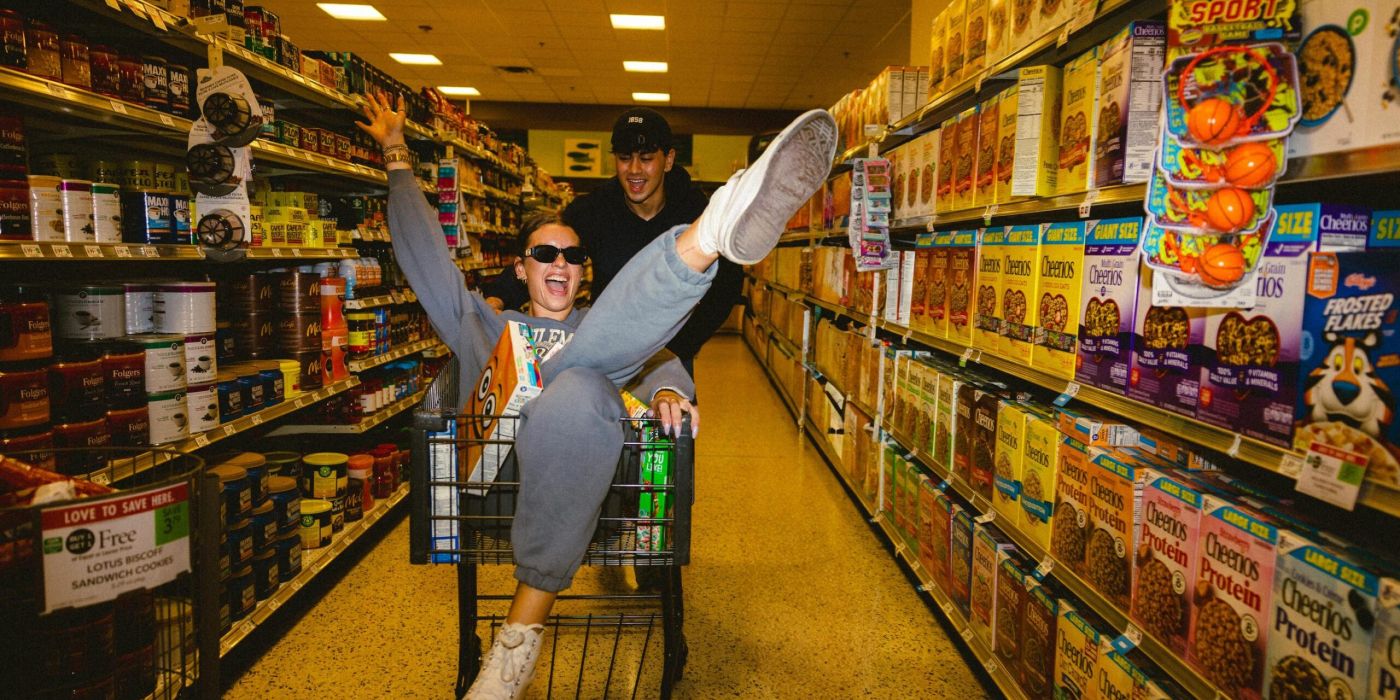 VERVE Orlando two people in a grocery store, one pushing a cart while the other sits inside with legs playfully in the air.