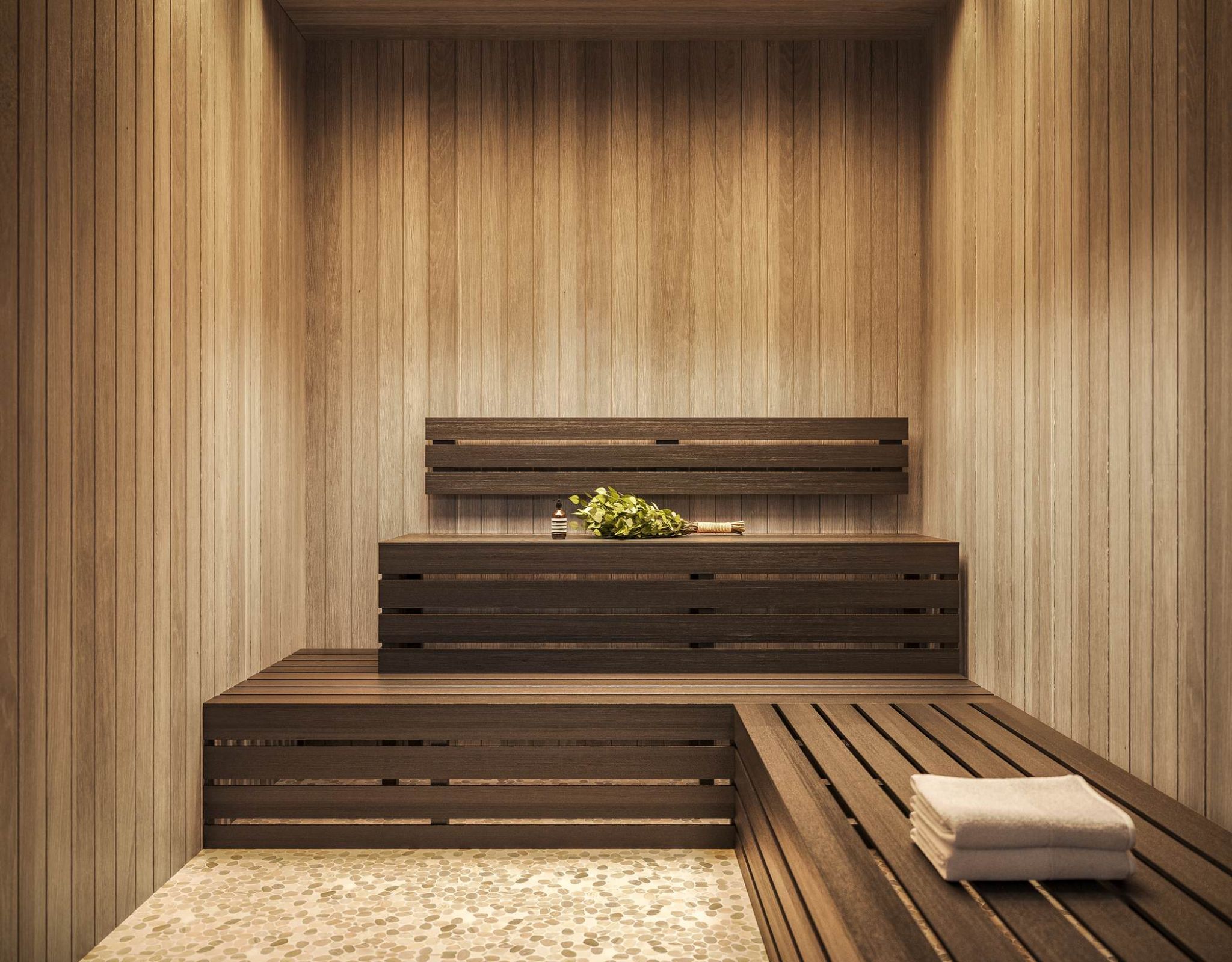 Modern wood-paneled sauna at VERVE Orlando featuring tiered bench seating, warm ambient lighting, and a serene, spa-like atmosphere for rest and recovery.