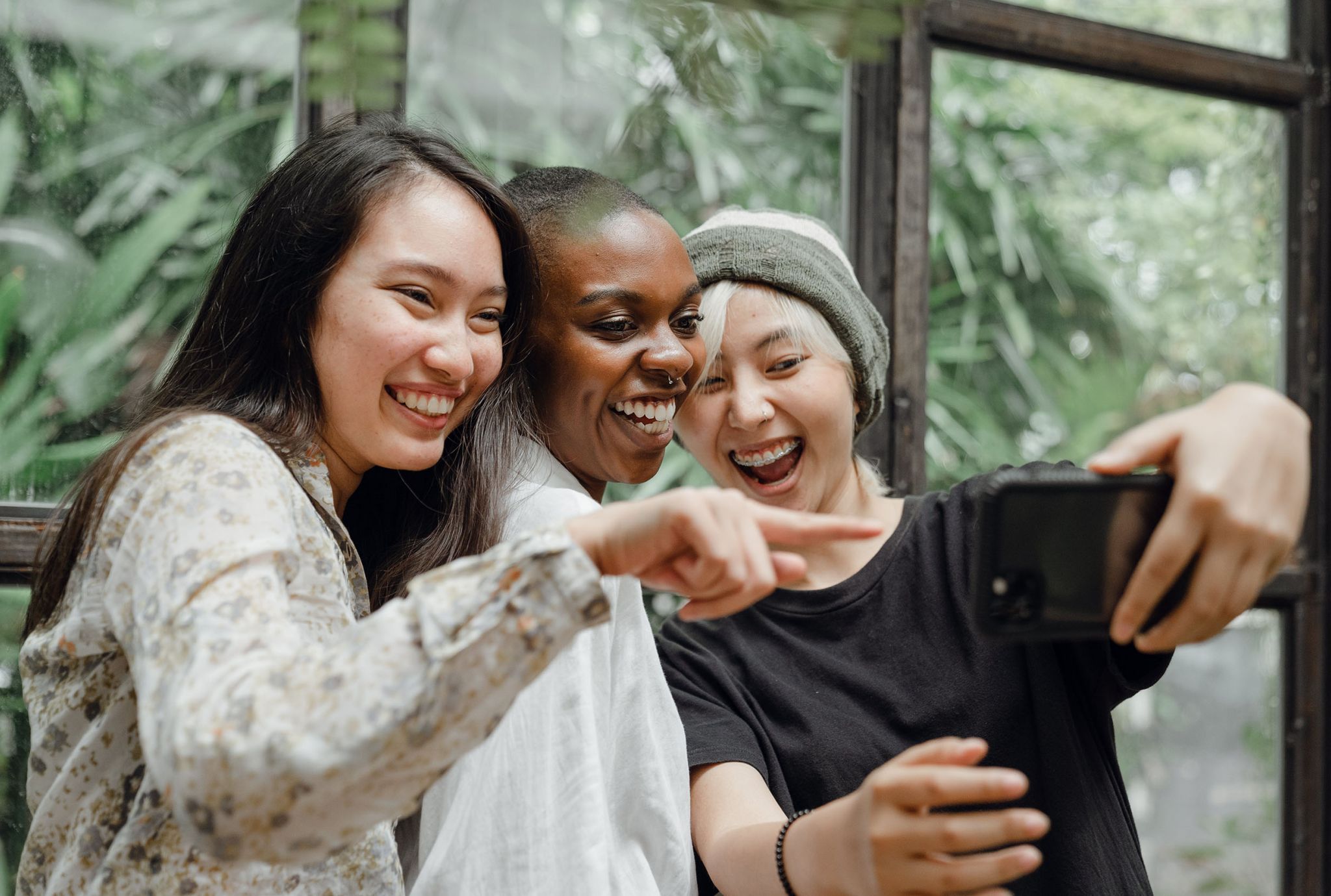 Tres estudiantes universitarios se apiñaban riéndose de algo en un teléfono.