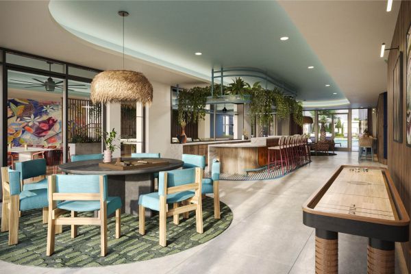 Spacious clubroom at VERVE Orlando featuring modern seating, a large central table, greenery accents, woven light fixtures, and a bar area—perfect for studying, lounging, or hosting friends.