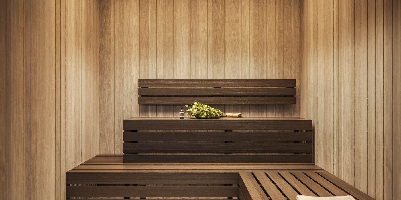 Modern wood-paneled sauna at VERVE Orlando featuring tiered bench seating, warm ambient lighting, and a serene, spa-like atmosphere for rest and recovery.