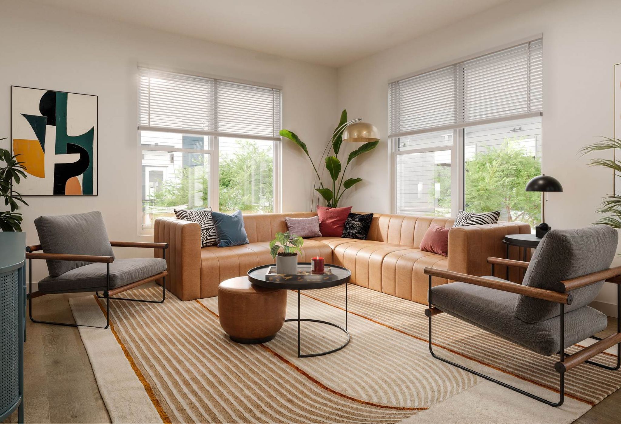La amplia y elegante sala de estar del VERVE Orlando cuenta con un gran sofá modular de color tostado, modernas sillas decorativas, alfombras superpuestas, exuberante vegetación y luz natural que entra a raudales por los enormes ventanales.