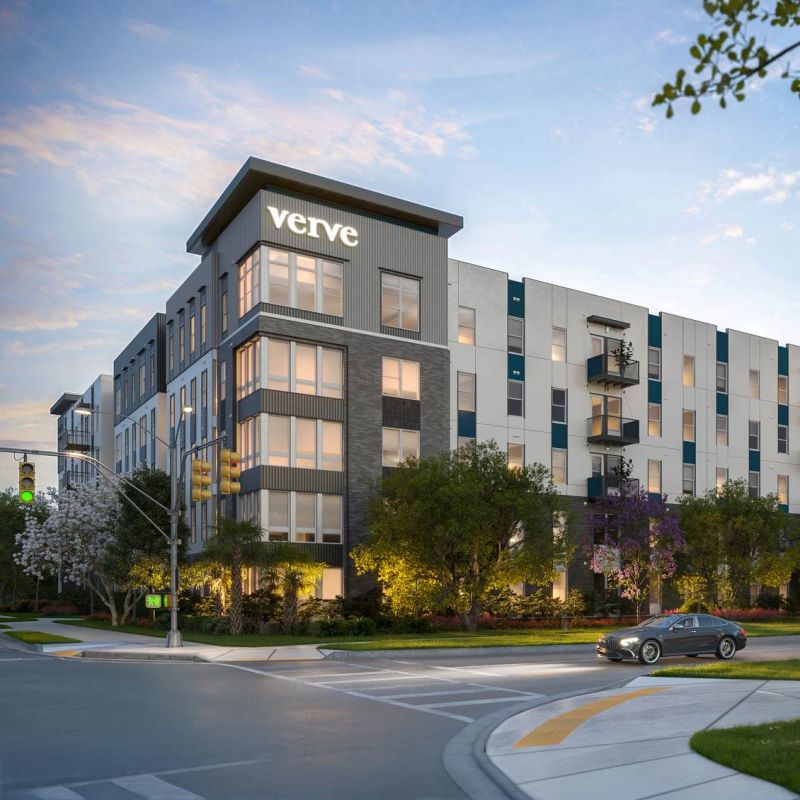 Vista exterior de VERVE Orlando, que muestra su diseño elegante y moderno con balcones privados, exuberantes jardines y una rotonda bajo un suave cielo vespertino.