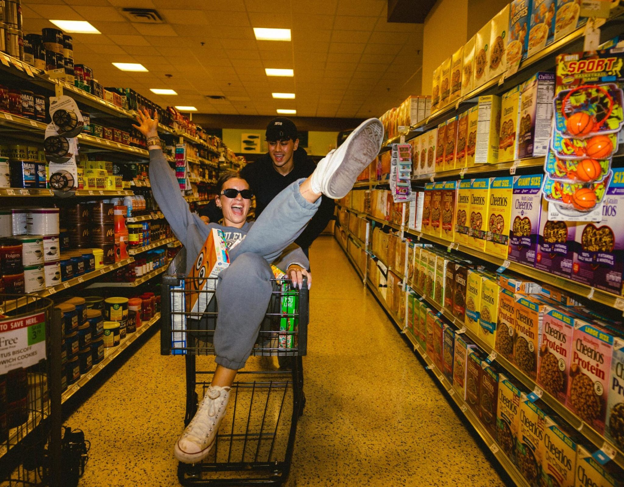 VERVE Orlando two people in a grocery store, one pushing a cart while the other sits inside with legs playfully in the air.