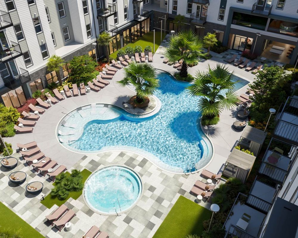 Vista aérea de la piscina estilo resort de VERVE Orlando, con una piscina en forma de laguna, jacuzzi, palmeras y filas de tumbonas rodeadas de modernos edificios de apartamentos.